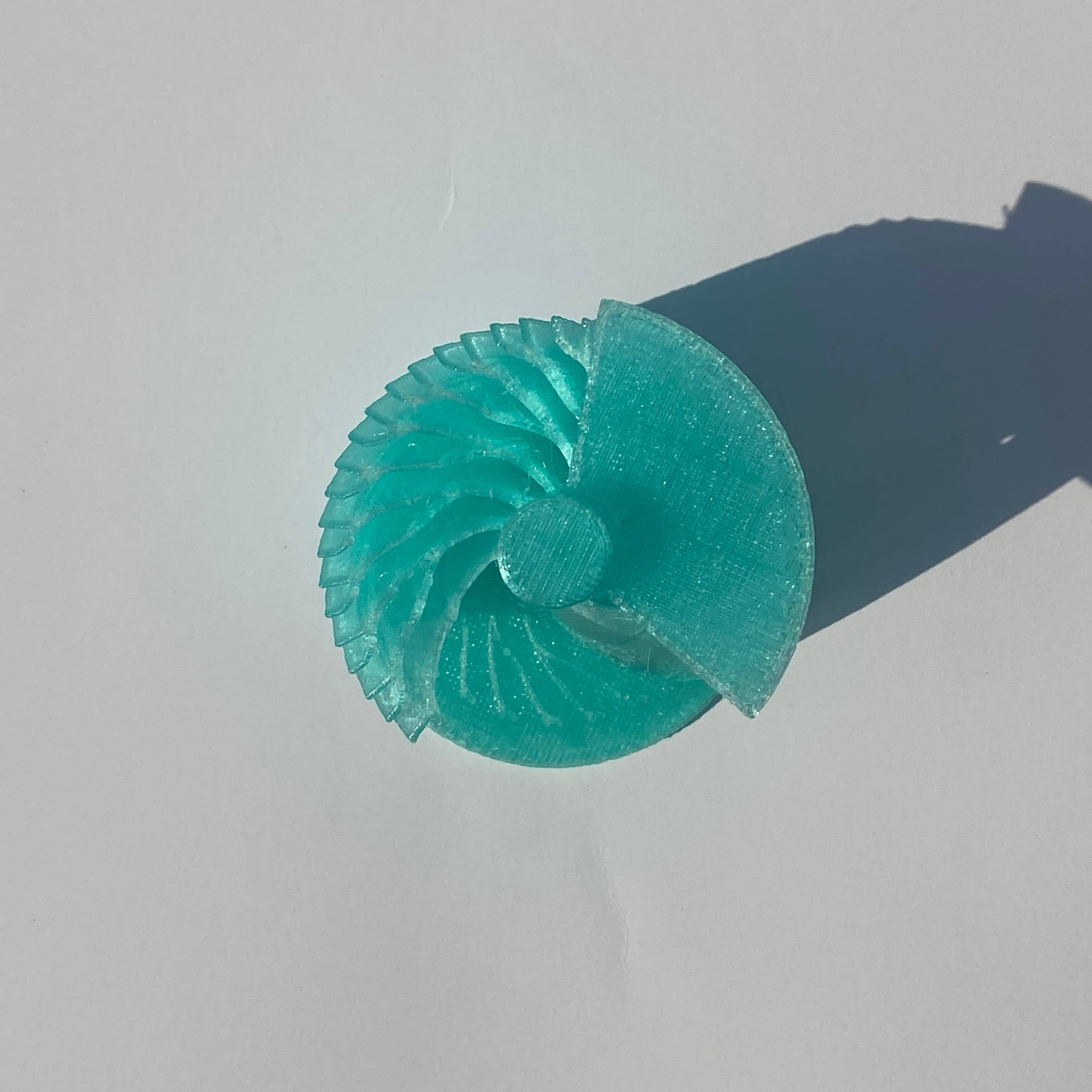 A spiral, fin-like concept geometry for a heat exchanger core, 3D printed in translucent teal polymer